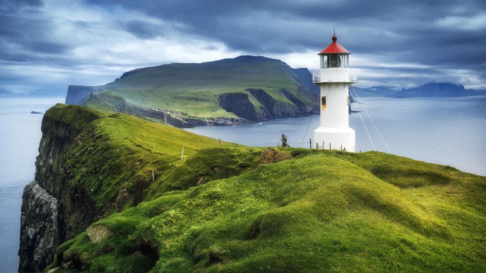 A lighthouse perched on a narrow spit of land next to the ocean